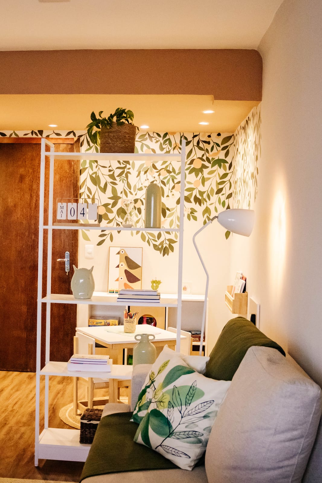 Sala de espera do consultório, com estante decorada, plantas e sofá aconchegante em tons naturais
