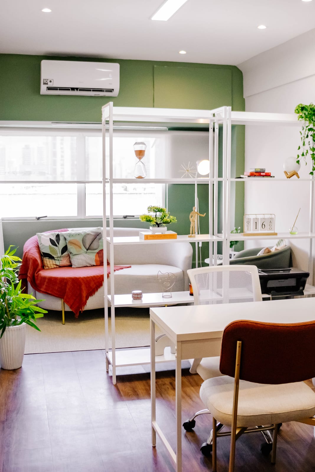 Sala de atendimento ampla e iluminada, com estante, sofá e mesa de trabalho