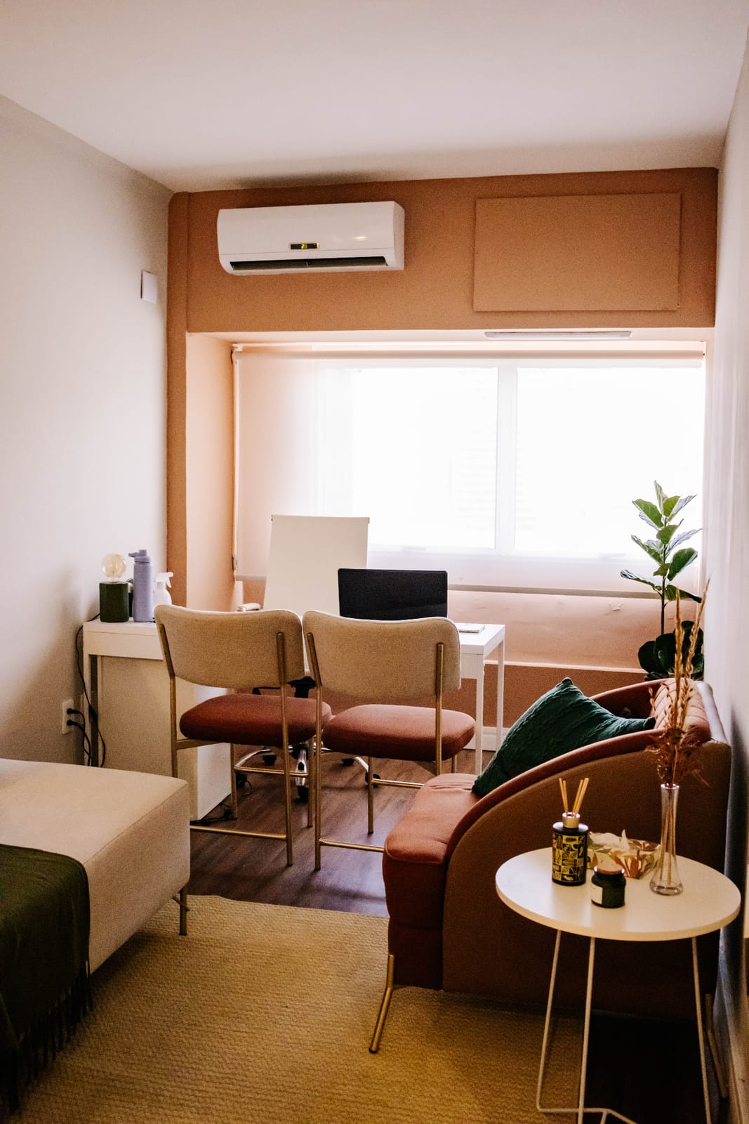 Sala de atendimento do consultório, com poltronas confortáveis, plantas e iluminação quente